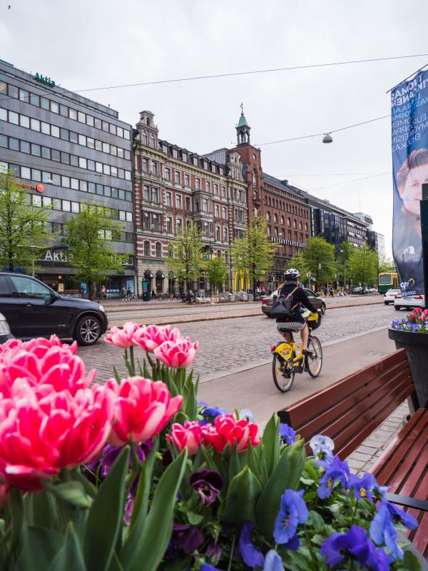 Cycling in Helsinki Female cyclist on the bicycle lane in central Helsinki, with flowers in the foreground.